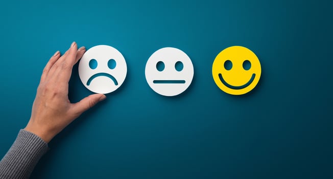 Rating concept. Woman choosing sad or bad smiley face emotion on green background, panorama, copy space photo