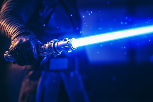 A man grips a bright blue lightsaber, showcasing power and creativity in a dynamic action pose in a dimly lit environment photo