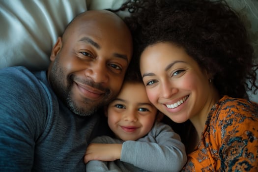 A joyful family enjoying quality time together in bed, cuddling and smiling with happiness on a cozy morning photo