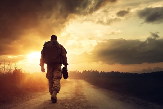 A patriotic soldier returns home at sunset after completing military service, walking along a dirt road amid a dramatic sky photo