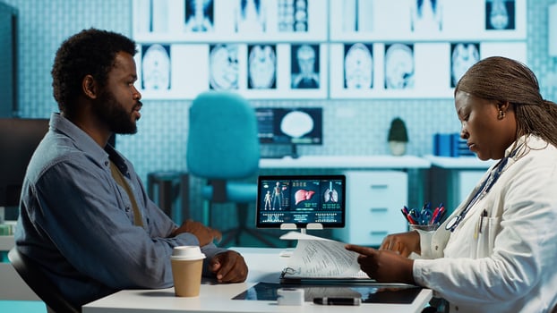 African american medic and patient engaging in detailed consultation with diagnostic tools, professional care and wellness. Doctor gives advice for disease prevention to young man. Camera A. photo