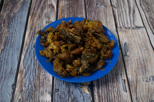 A blue plate filled with crispy fried chicken skin, served on a rustic wooden surface. photo