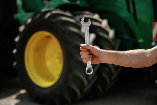 Close-up, of hand holding wrench in front of tractor photo