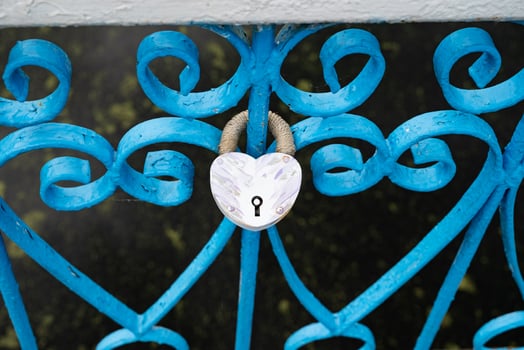 Heart-shaped lock on the fence on the background of other castles, water, concrete pavement photo