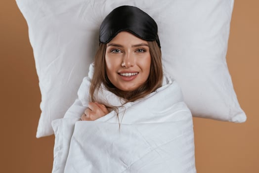 Wrapped in a blanket. Young pretty woman ,,is against background in the studio photo