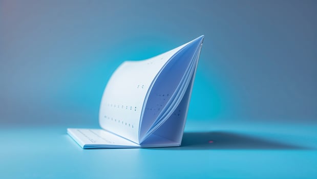 Unique design of an open notepad with perforated pages standing on a blue surface under soft lighting photo