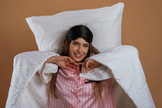 Just, woke up, in pajama and on the pillow. Young pretty woman is against background in the studio photo