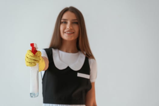 Chambermaid is with ,cleaning ,,product and tool. Young pretty woman is against background in the studio photo
