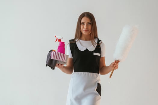 Chambermaid is with cleaning product ,,and tool. Young pretty woman is against background in the studio photo