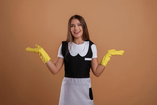 Brown backdrop, chambermaid is standing... Young pretty woman is against background in the studio photo