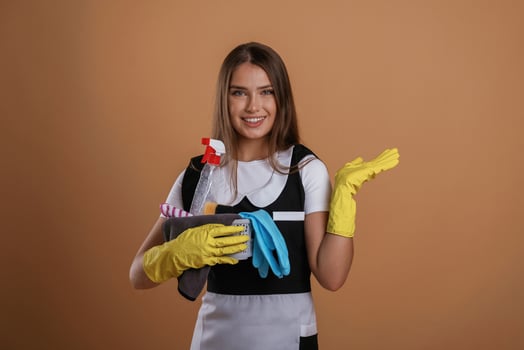 Yellow, gloves, chambermaid ,is ,,with cleaning products. Young pretty woman is against background in the studio photo