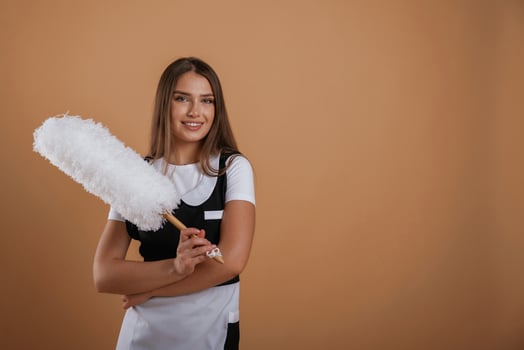Beautiful ,chambermaid is holding .cleaning brush. Young pretty woman is against background in the studio photo