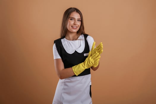 Done,, work is finished, chambermaid is in yellow gloves. Young pretty woman is against background in the studio photo