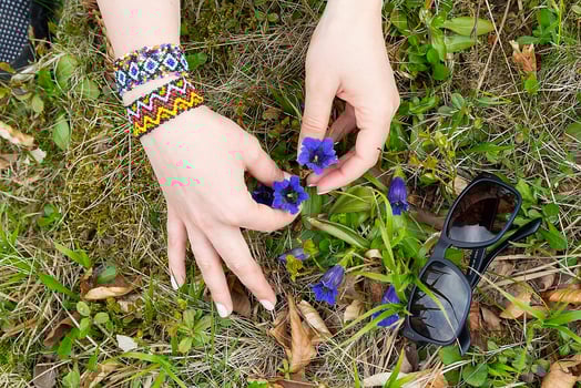 Female hands with bracelet and wildflowers photo