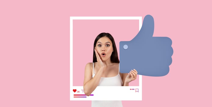 A young woman with long dark hair shows excitement and surprise while holding a large thumbs up sign. Bright pink background enhances the cheerful vibe of social media engagement. photo