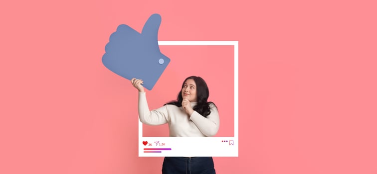A person stands against a bright pink background, holding a large thumbs up sign, expressing excitement about social media engagement. They appear enthusiastic and ready to create content. photo