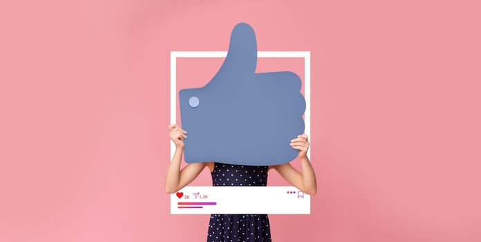 A person is holding a large thumbs up symbol in front of a bright pink background. This vibrant display emphasizes social media engagement, showcasing enthusiasm for content creation. photo