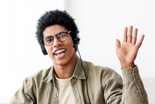 Web-based communication concept. Black teen guy talking to his college tutor on laptop computer from home. Positive African American youth waving to his fellow students during online conference photo