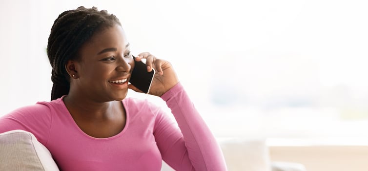 Cheerful Black Lady Talking On Cellphone While Relaxing On Couch At Home, Having Plesant Phone Conversation, Smiling African Lady Enjoying Mobile Communication, Chatting With Friends, Copy Space photo