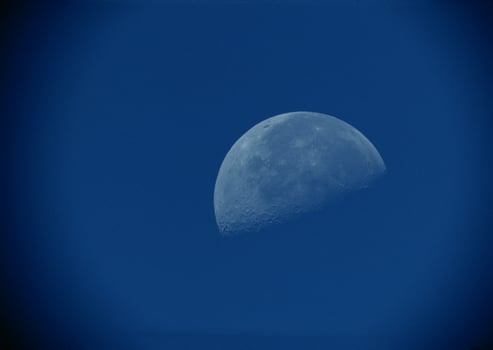the moon is seen in a blue sky photo