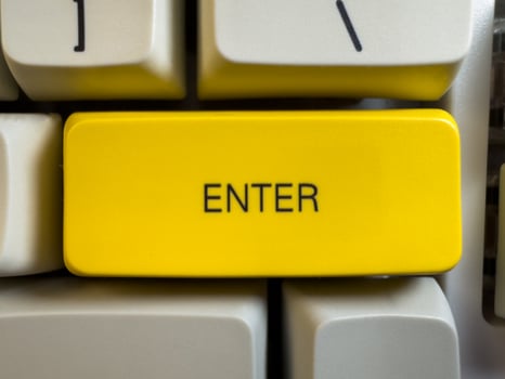 Large yellow Enter button on mechanical white keyboard for programmers with gray shades and red switches, flay lay, copy space photo