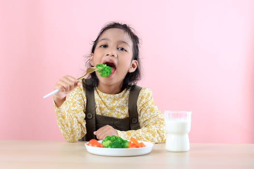 Asian Girl Eating Healthy Vegetables and Drinking Milk photo