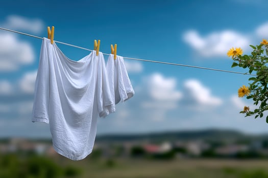 White laundry hanging on a clothesline against a scenic backdrop of blue sky and clouds photo