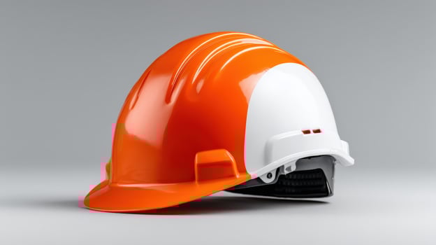Construction safety helmet in bright orange and white colors on a plain background photo