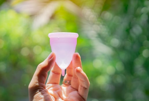 Woman's period, menstrual cup in hands over real nature background, modern methods for crytical days. photo