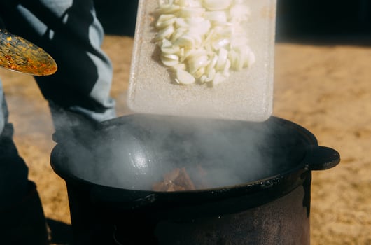 Meat cooking in a large cauldron outdoors over an open fire, a classic outdoor cooking concept for camping and traditional cuisine photo