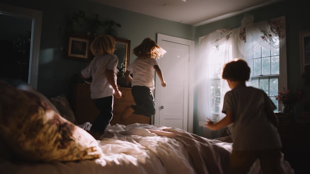 Children jump joyfully on a bed in a well-lit bedroom during a sunny afternoon photo
