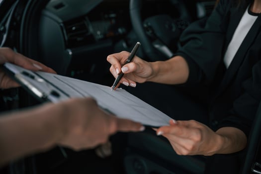 Process of buying new ,car, woman is signing documents while sitting in a new automobile photo