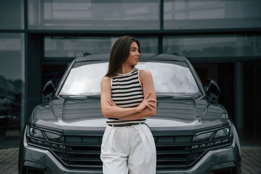 Attractive, young woman is outdoors near her brand new car photo