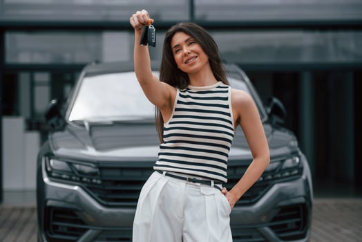 Happy, owner of the new car with keys. Attractive young woman is outdoors near her brand new car photo