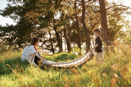 With blanket,,, putting it on the ground. Mother and son are in the forest together photo