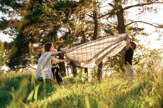 With ,blanket,,, putting it on the ground. Mother and son are in the forest together photo