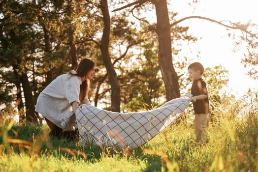 Preparing for picnic, with blanket... Mother and son are in the forest together photo