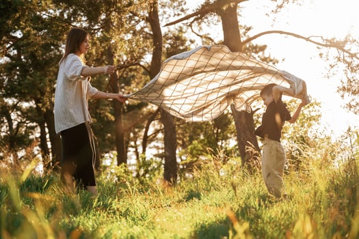 Preparing, for, picnic, with blanket. Mother and son are in the forest together photo