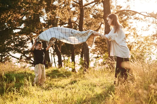 With ,blanket, putting it on the ground. Mother and son are in the forest together photo