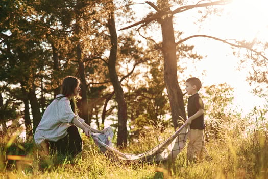 Preparing ,for picnic, with blanket. Mother and son are in the forest together photo