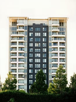 tall dark apartment building stands prominently against a bright sky. photo