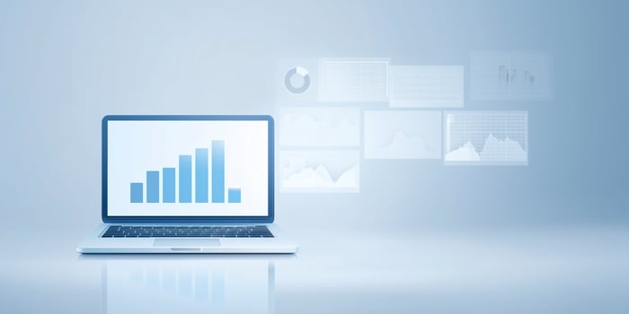 Laptop displaying a bar graph on screen with data visualizations in background, modern workspace concept photo