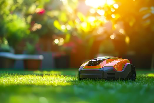 Autonomous robotic lawn mower cutting grass in garden at sunset photo