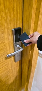 Hand holding key card to unlock modern hotel door with wooden finish photo