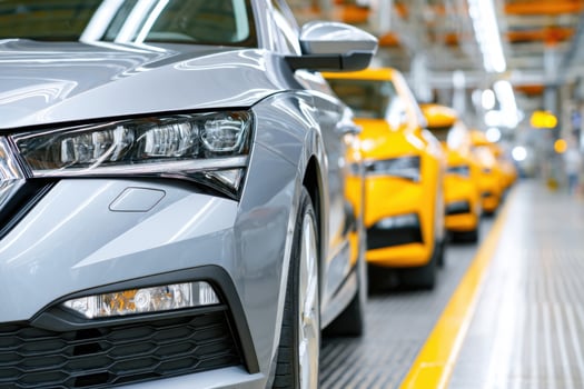 Silver sedan parked in a modern automotive assembly line, showcasing sleek design and advanced engineering, with vibrant yellow vehicles in the background highlighting production efficiency photo