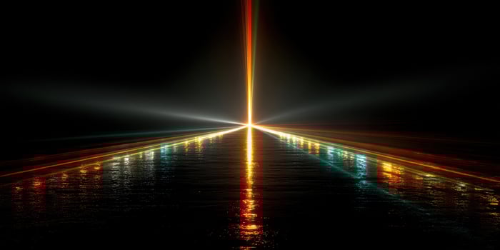 Bright beams of light pierce through darkness over a reflective surface at night photo