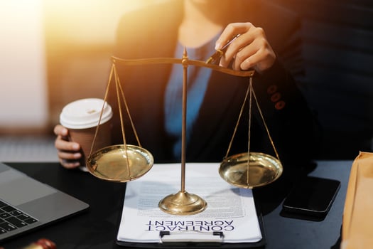 Businesswoman holding scales of justice on desk with coffee and laptop photo