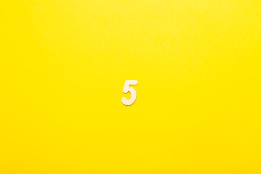 Top view of wooden number 5 five on yellow bright background. photo