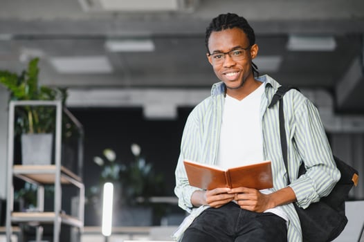 Smiling african american student reading book in university library photo