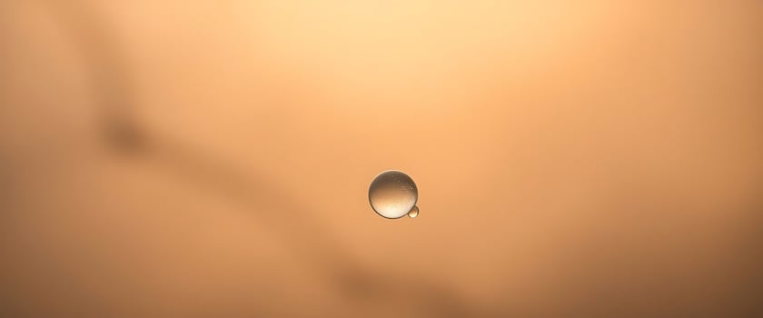 drop of water sitting on top of a brown surface photo